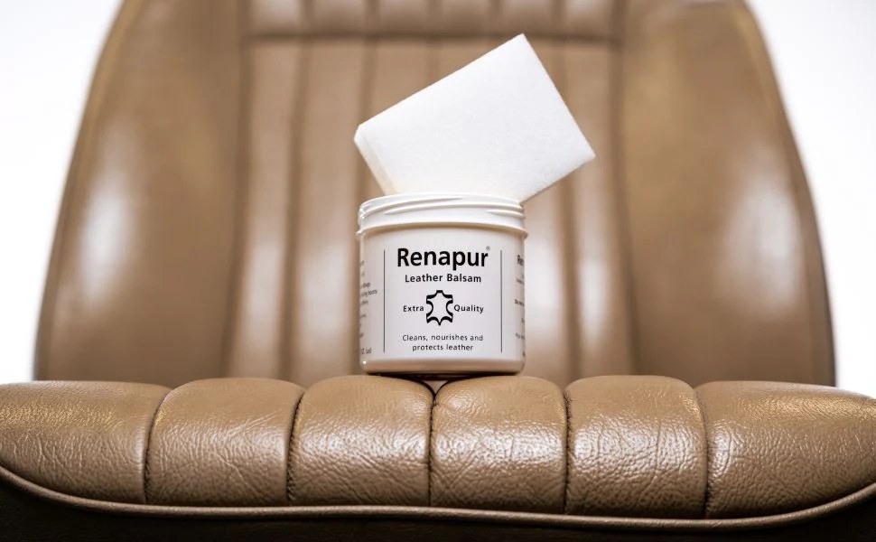 A jar of Renapur Leather Balsam resting on a tan leather chair